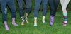 five people wearing colorful socks standing on grass