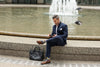 a man sitting by a fountain wearing colorful socks